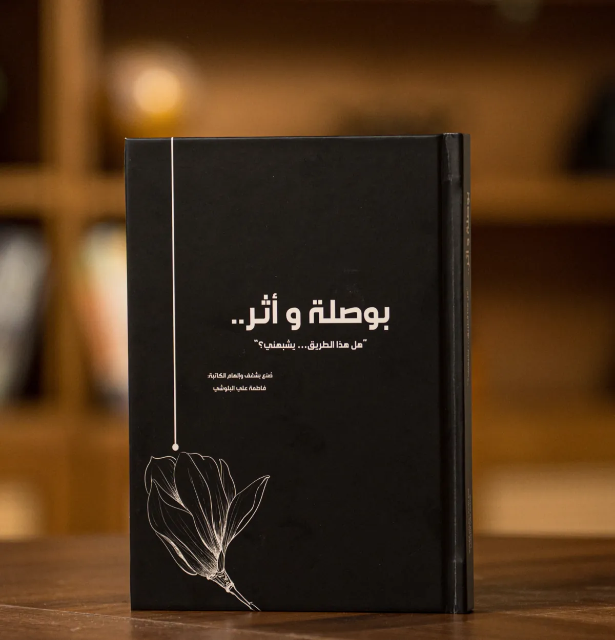 غلاف دفتر «بوصلة وأثر» الأسود: خط رفيع ينتهي بنقطة فوق زهرة، وعنوان «هل هذا الطريق… يشبهني؟»